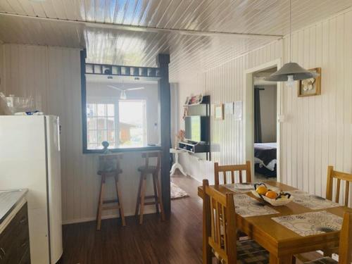 a kitchen and dining room with a table and a refrigerator at Chalé Vale do Floresta in Gramado