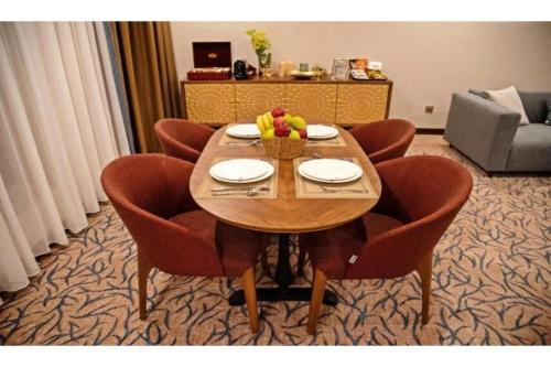 a wooden table with chairs and a bowl of fruit on it at Sunday Emerald Hotel in Jeddah