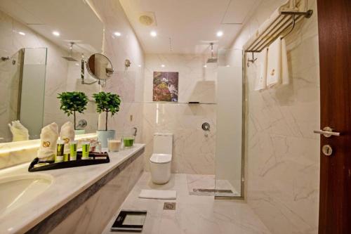 a bathroom with a tub and a toilet and a sink at Sunday Emerald Hotel in Jeddah