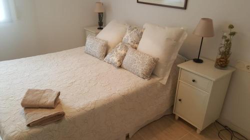 a bedroom with a white bed with pillows and a night stand at Casa Roc de Sant Gaietà in Comarruga