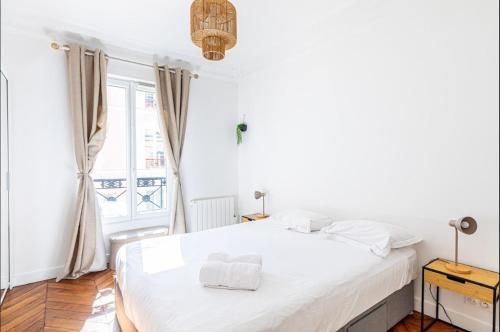 une chambre blanche avec un grand lit et une fenêtre dans l'établissement GuestReady - Lovely retreat near the Eiffel Tower, à Paris