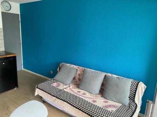 - un canapé dans une chambre dotée d'un mur bleu dans l'établissement Cozy and modern studio, à La Grande Motte