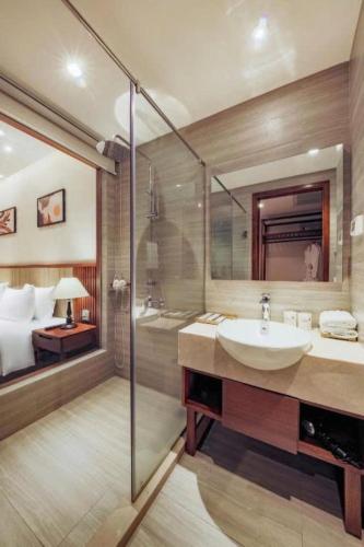 a bathroom with a sink and a shower and a bed at Green Beach Hotel Nha Trang in Nha Trang