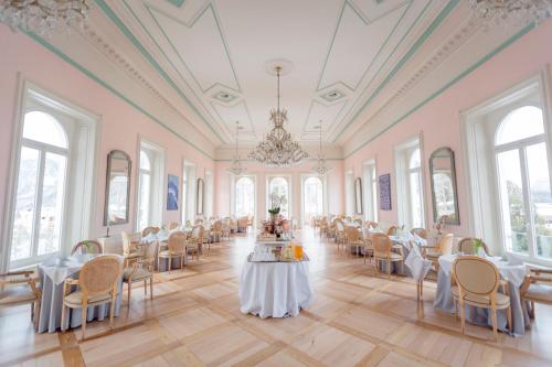 una sala banchetti con tavoli, sedie e lampadario a braccio di Kleos Hotel Bernina 1865 a Samedan