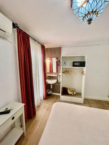 a bedroom with a bed with red curtains and a desk at Pension Zurita in Granada