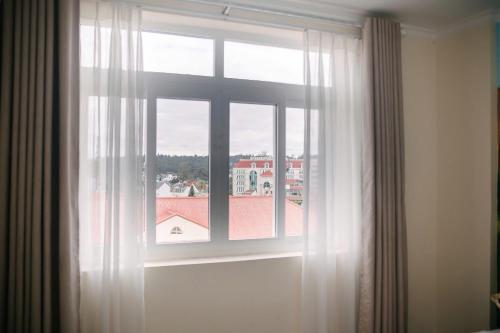 a window with white curtains and a view of a building at Đoàn An điều dưỡng 198 in Xuan An