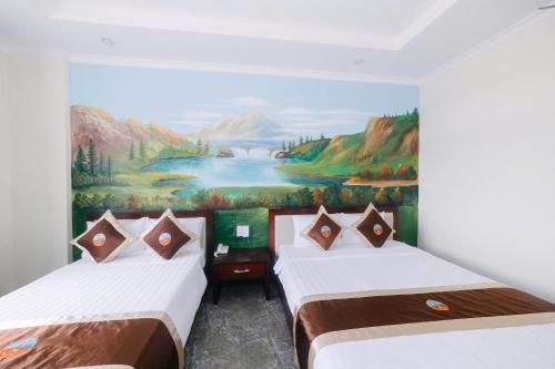 two beds in a room with a painting on the wall at Đoàn An điều dưỡng 198 in Xuan An