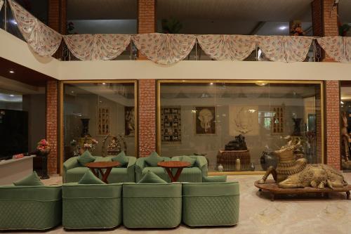 a lobby with green chairs and tables in a building at Hotel Sai Palkhi Niwara in Shirdi