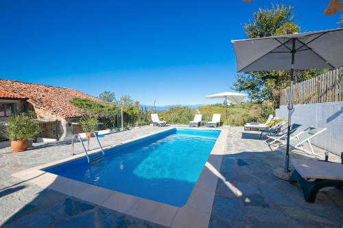 a swimming pool with an umbrella next to a house at In Bocca Al Lupo with Shared Pool in Clavesana