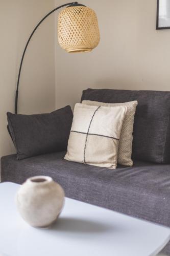 a couch with pillows and a lamp on a table at Magnifique 2 pièces rénové aux Sources in Vieux Kouba