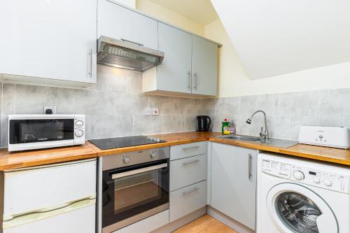 a kitchen with white cabinets and a washer and dryer at Camden Apartments in London