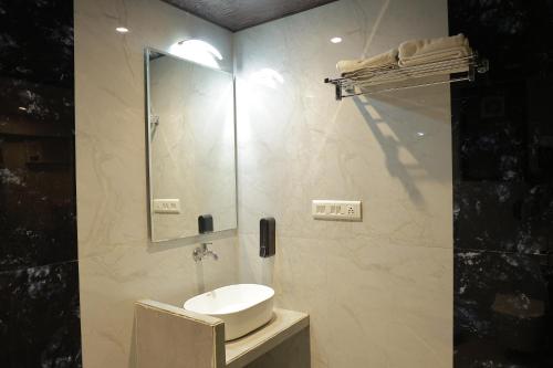 a bathroom with a sink and a shower with a mirror at Hotel Sai Palkhi Niwara in Shirdi