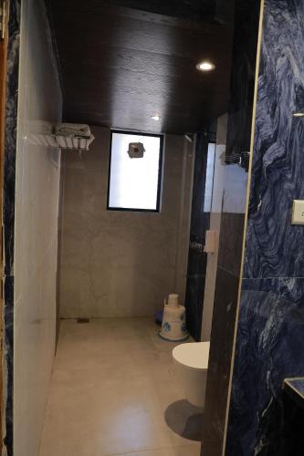 a bathroom with a toilet and a sink and a window at Hotel Sai Palkhi Niwara in Shirdi