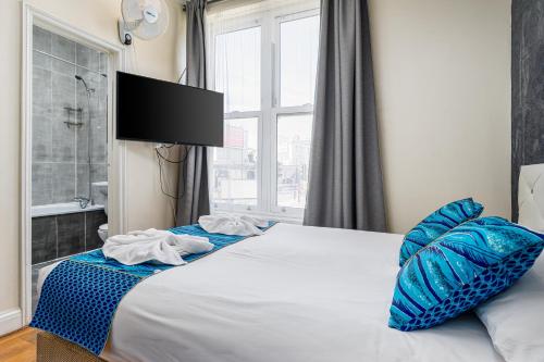 a bedroom with a bed with blue pillows and a window at Camden Apartments in London
