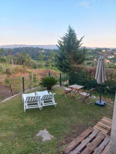 two white chairs and an umbrella on a yard at Al Do Paço - Between Braga e Geres in Amares