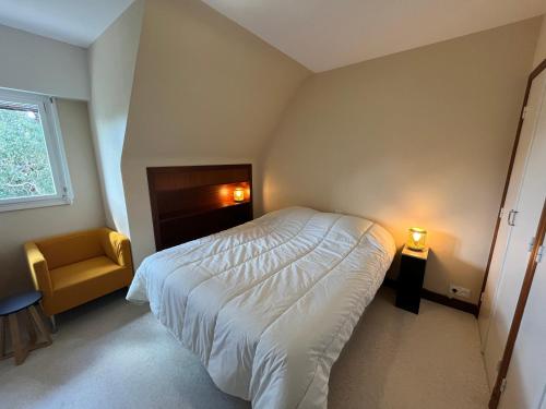 une chambre avec un lit blanc et une chaise dans l'établissement Proche Plage LÉGENÈSE - 1143, à Carnac