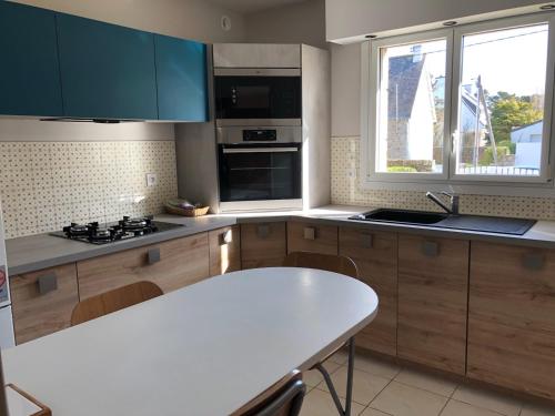 - une cuisine avec des placards en bois et une table blanche dans l'établissement Proche Plage LÉGENÈSE - 1143, à Carnac