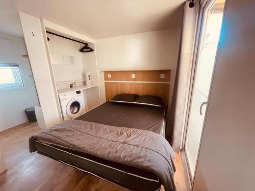 une petite chambre avec un lit dans une pièce dans l'établissement Mobil Home Oliviers 3, à Valras-Plage