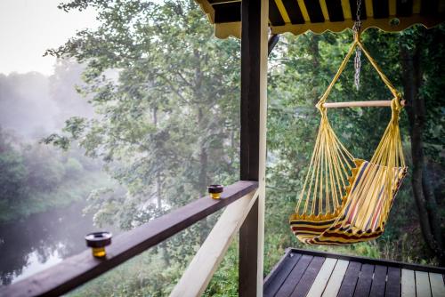 a hammock on a porch with a view of a forest at Kaimo turizmo sodyba Geras in Leliūnai