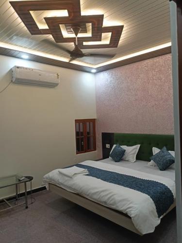 a bedroom with a large bed with a ceiling at Snerola family hotel in Bhauli