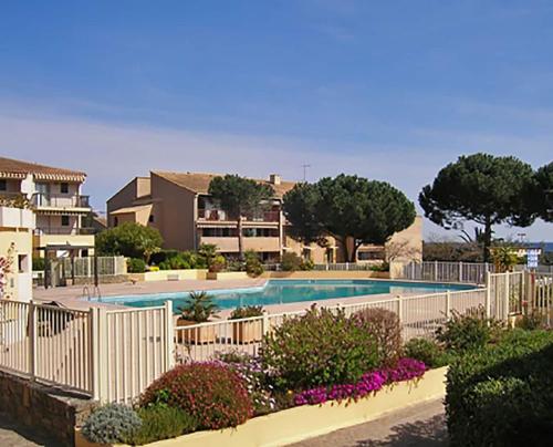 - une piscine avec une clôture blanche et des fleurs dans l'établissement Studio 3 étoiles - parking - wifi - clim - piscine, à Roquebrune-sur Argens
