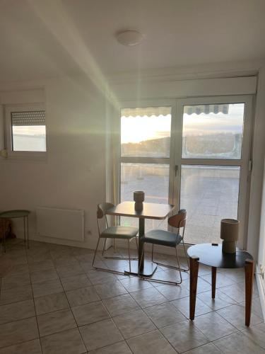 une table et des chaises dans une pièce avec une fenêtre dans l'établissement le studio de la mer, à Saint-Valery-en-Caux