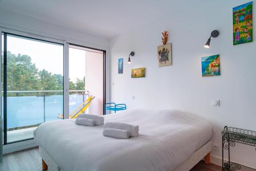 - une chambre blanche avec un grand lit et une grande fenêtre dans l'établissement La perle de Men Er Beleg - Appt vue mer de 167m², à Saint-Philibert