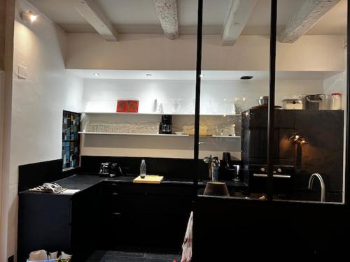 a kitchen with black counters and a large window at Pierres anciennes et soirées douces Coeur de ville in Pézenas