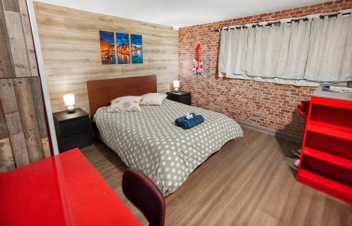 a bedroom with a bed and a brick wall at Double Studio Dijon CHU, Cinéma, Jardin & Parking in Dijon