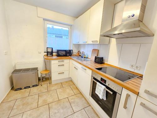 a kitchen with white cabinets and a stove top oven at EcoCube 141 - Terrasse, 3Zimmer, Waschmaschine, Backofen, 5Pers in Meppen