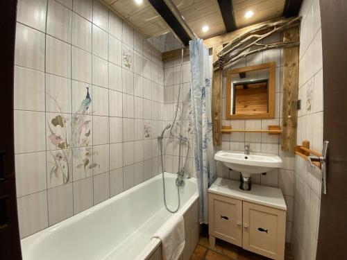 a bathroom with a tub and a sink and a bath tub at LA POMME DE PIN 1 Appartement avec terrasse in La Bresse