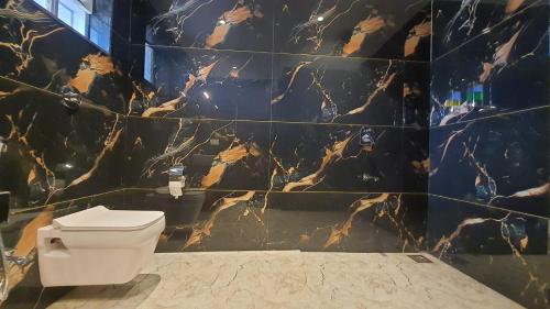 a bathroom with a toilet and a marble wall at The Mountain Paradise Mahabaleshwar in Kelghar