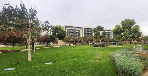 a park with trees and a building in the background at Madinaty apartment 4 شقة فندقية مفروشة سوبر لوكس في مدينتي in Madinaty