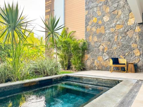 a swimming pool with a chair next to a stone wall at Blue Zebra - T4 Oasis - Rivière, Mer et Piscine in Rivière Noire