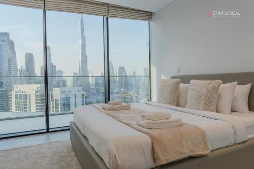 two beds in a bedroom with large windows at Experience Iconic Burj Khalifa Views from Your Cozy Getaway with Pool in Dubai