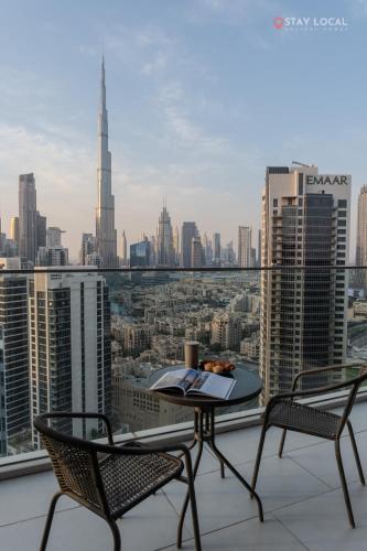 a table and chairs on a balcony with a view of a city at Experience Iconic Burj Khalifa Views from Your Cozy Getaway with Pool in Dubai