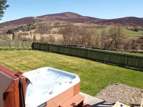 a hot tub in a yard with a hill at Coo Shed in Glenshee
