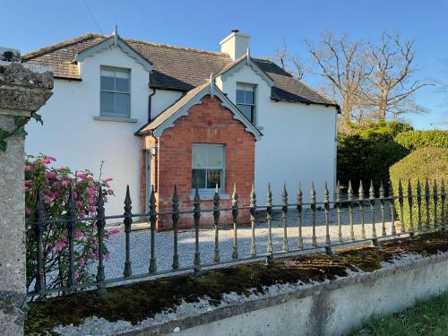 a fence in front of a white house at Mizzle Cottage in Cloghjordan