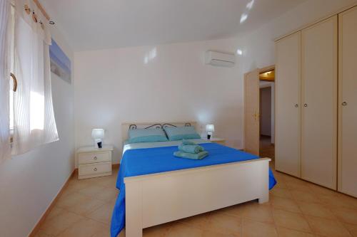 um quarto com uma cama com lençóis azuis e travesseiros azuis em Il giardino di Marina em Teulada