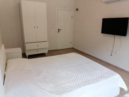 a bedroom with a white bed and a flat screen tv at Erme Dinlenme Tesisleri in Dernekpazarı