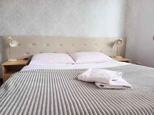a bed with white sheets and two lamps on tables at Hotel i Restauracja Borowianka in Ostrów Wielkopolski