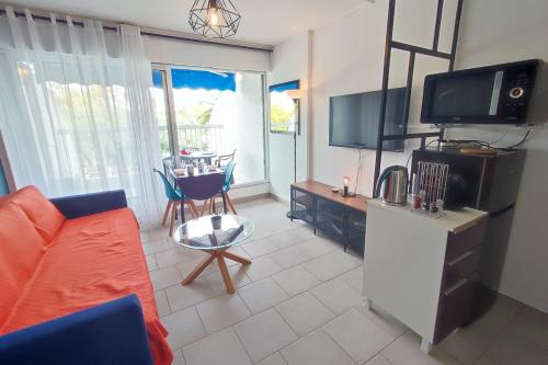 un salon avec un canapé et une table avec des chaises dans l'établissement 1st line modern studio-private parking, à La Grande Motte
