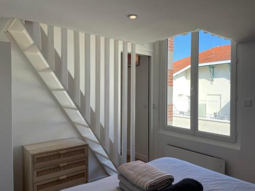 ein Schlafzimmer mit einer Treppe und einem Bett und einem Fenster in der Unterkunft Arcachon Centre - Le 33 Tartas - Parking Inclus in Arcachon