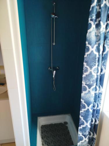 La salle de bains est pourvue d'une douche avec un mur bleu. dans l'établissement Gîte au charme champêtre, à Guern