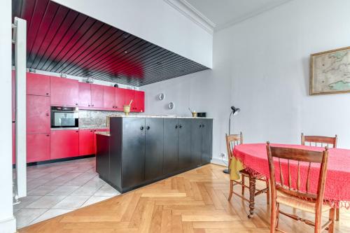 une cuisine avec des placards rouges et une table rouge avec des chaises dans l'établissement GuestReady - Elegant Getaway in Central Lyon, à Lyon