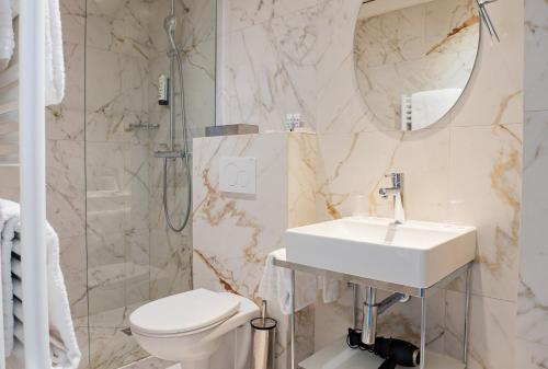 a bathroom with a sink and a toilet and a shower at Hôtel Edouard 6 by Malone in Paris