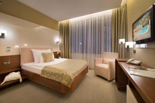 a hotel room with a bed and a chair and a television at Wellness Hotel Diamant in Hluboká nad Vltavou
