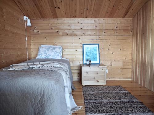 a bedroom with a bed and a wooden wall at Cozy 4BR Lakeside Cottage with Sauna & Outdoor Grill in Lahti