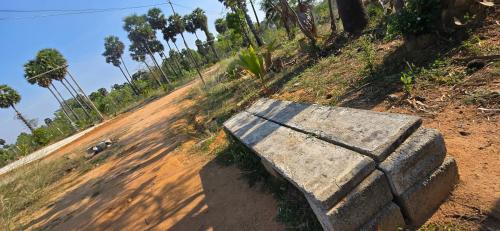 a stone bench sitting on the side of a dirt road at KK Dream Garden in Kāraikkudi