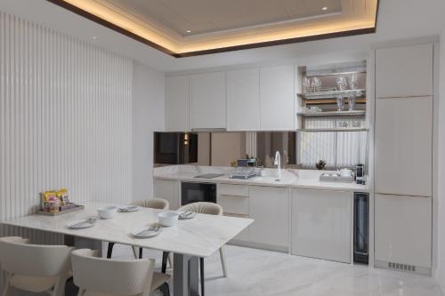 a kitchen with white cabinets and a table and chairs at La Plante Siem Reap in Siem Reap